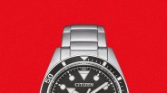 Silver Citizen wristwatch with black textured dial and luminous markers on a red background.