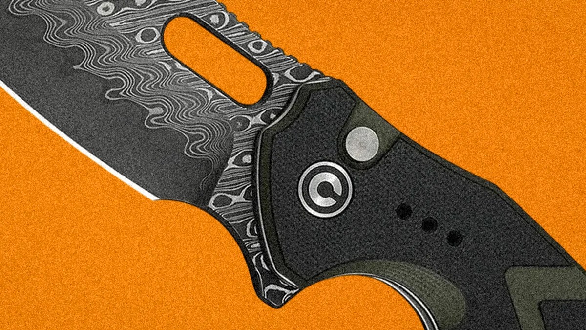 Close-up of a folding knife with a patterned Damascus steel blade and a black textured handle on an orange background.