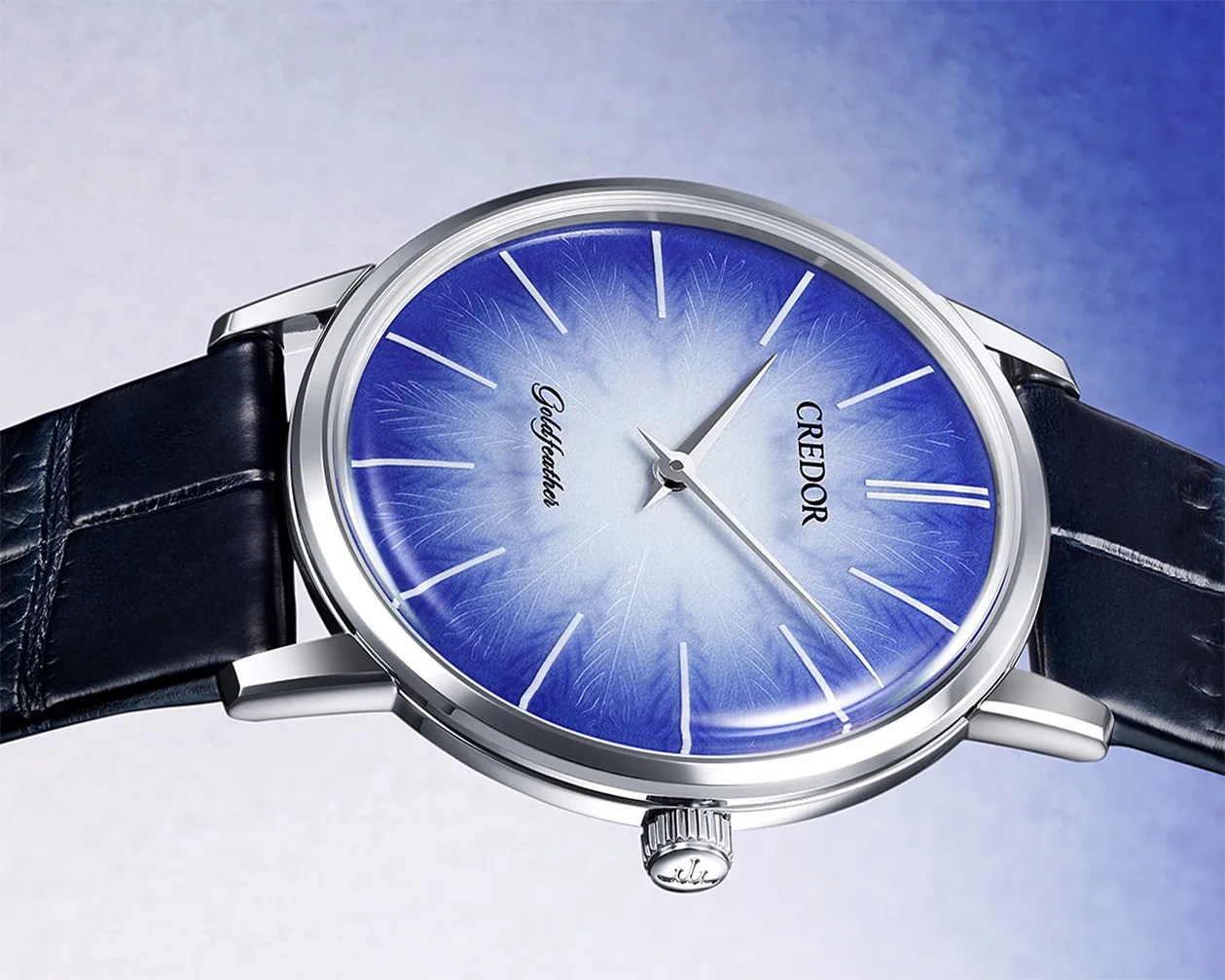 Silver wristwatch with a gradient blue and white dial, thin silver hands, and a black leather strap.