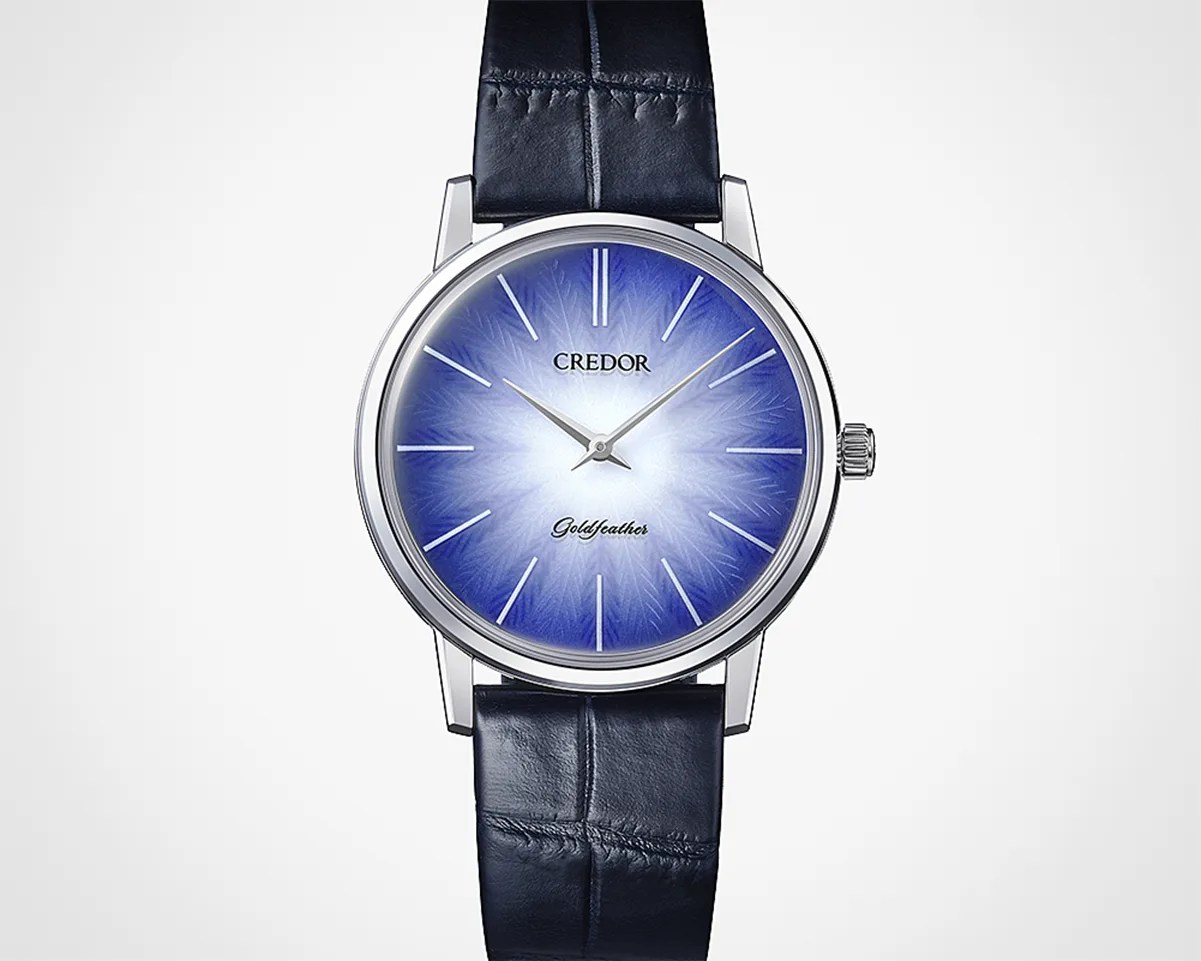 Silver wristwatch with a blue gradient dial featuring a feather-like pattern and a black leather strap.