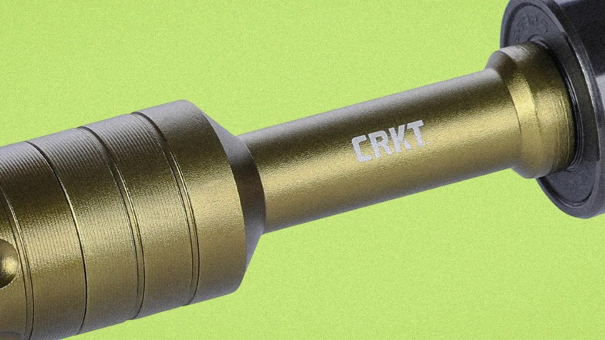 Close-up of a metallic gold cylindrical object with the white "CRKT" logo on a green background.