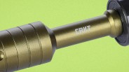 Close-up of a metallic gold cylindrical object with the white "CRKT" logo on a green background.