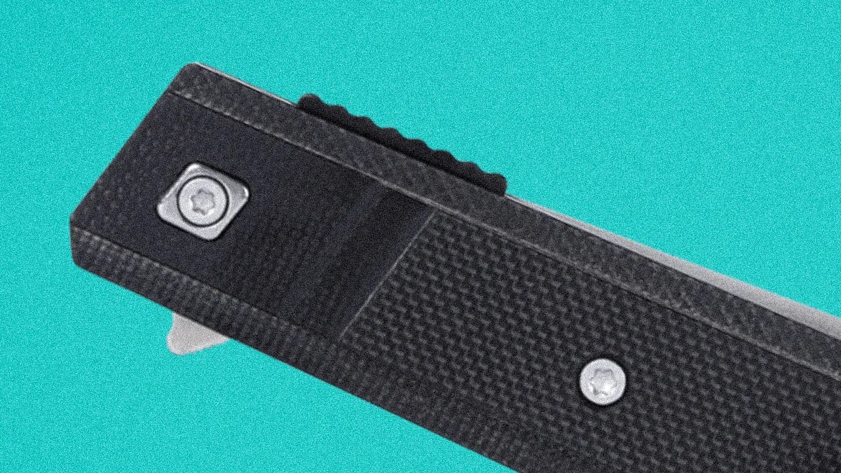 Close-up of a black textured folding knife handle with two silver screws on a turquoise background.