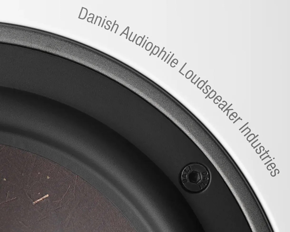 Close-up of a black speaker cone with a screw and the text "Danish Audiophile Loudspeaker Industries" on a white background.