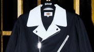 Black jacket with large white collar and white zippered chest pocket hanging on a Schott hanger.