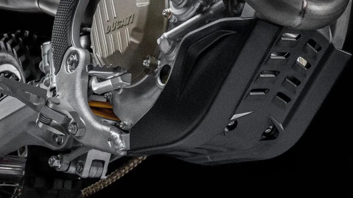 Close-up of a Ducati motorcycle engine with a black skid plate and part of the footpeg and chain visible.