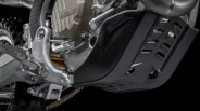 Close-up of a Ducati motorcycle engine with a black skid plate and part of the footpeg and chain visible.