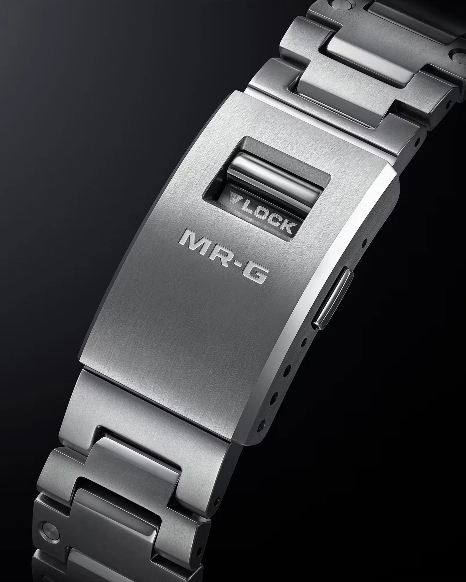 Brushed silver metal watch clasp with "MR-G" and "LOCK" engravings on a linked bracelet.