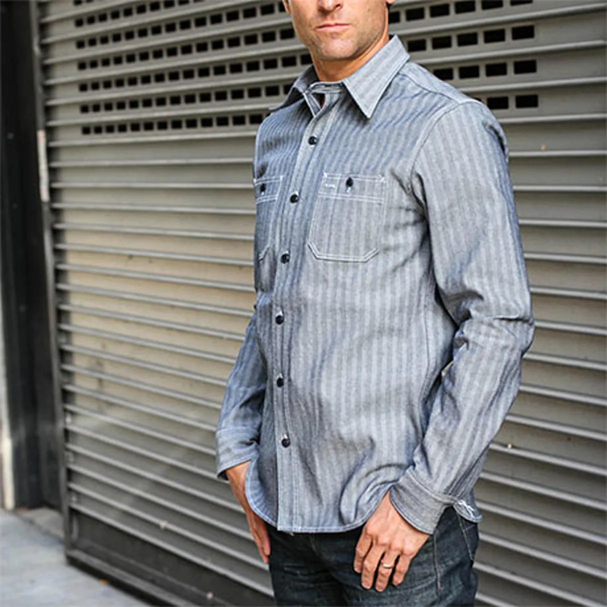 Gray long-sleeve button-up shirt with vertical stripes and chest pockets worn by a person.