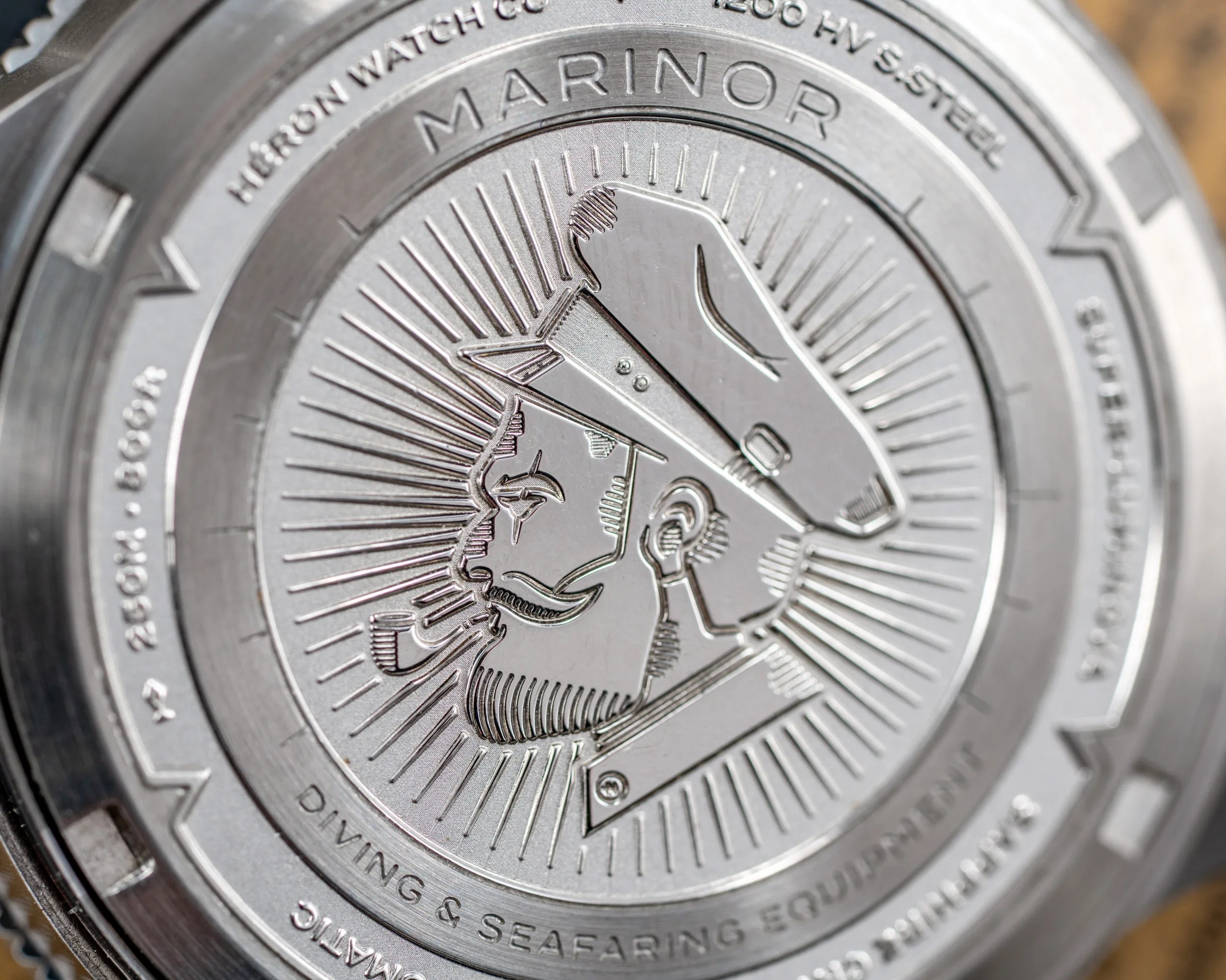 Close-up of a silver watch back engraved with a bearded sailor wearing a cap and smoking a pipe, labeled "MARINOR.