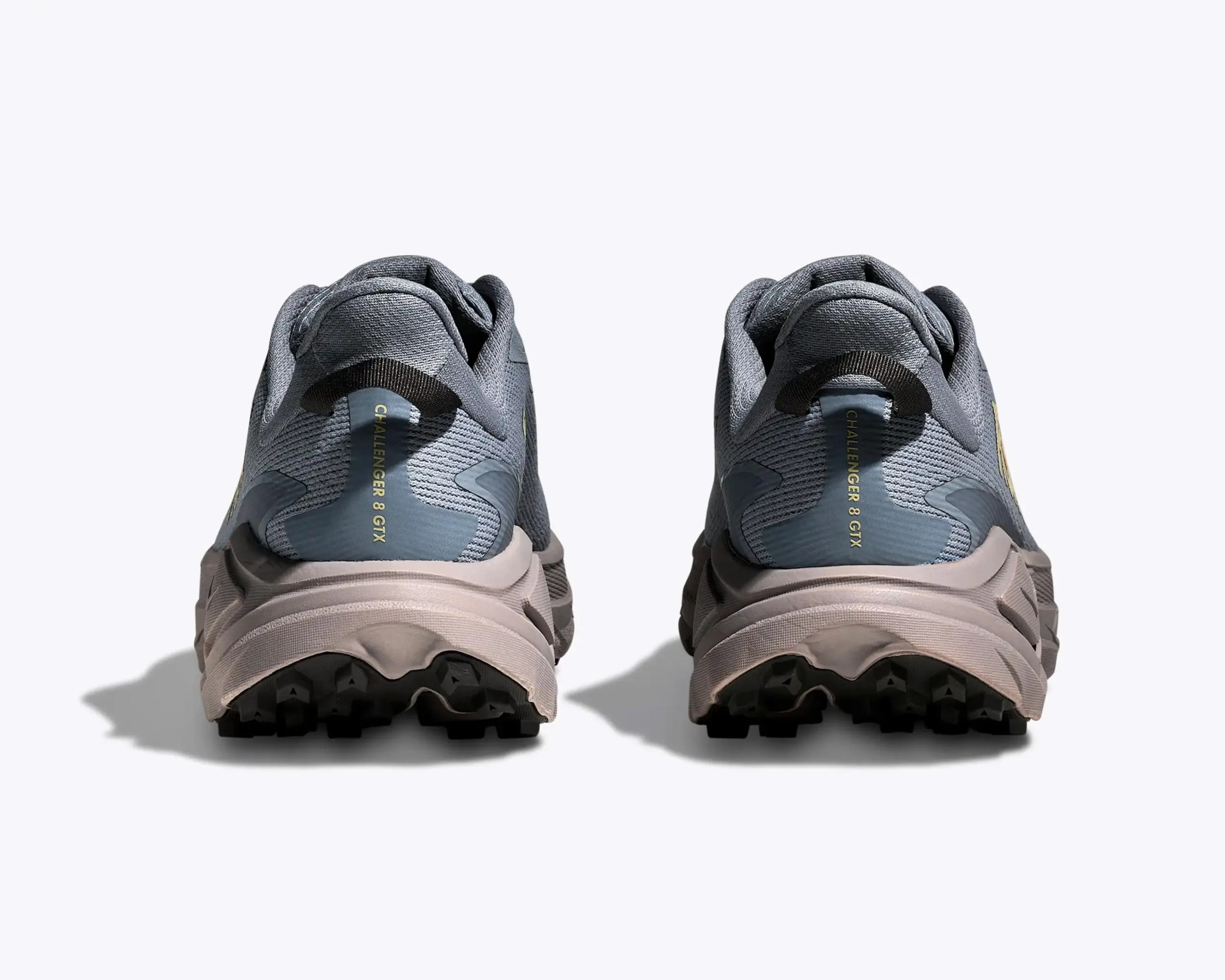 Pair of gray and beige trail running shoes with black rugged soles, viewed from the back.