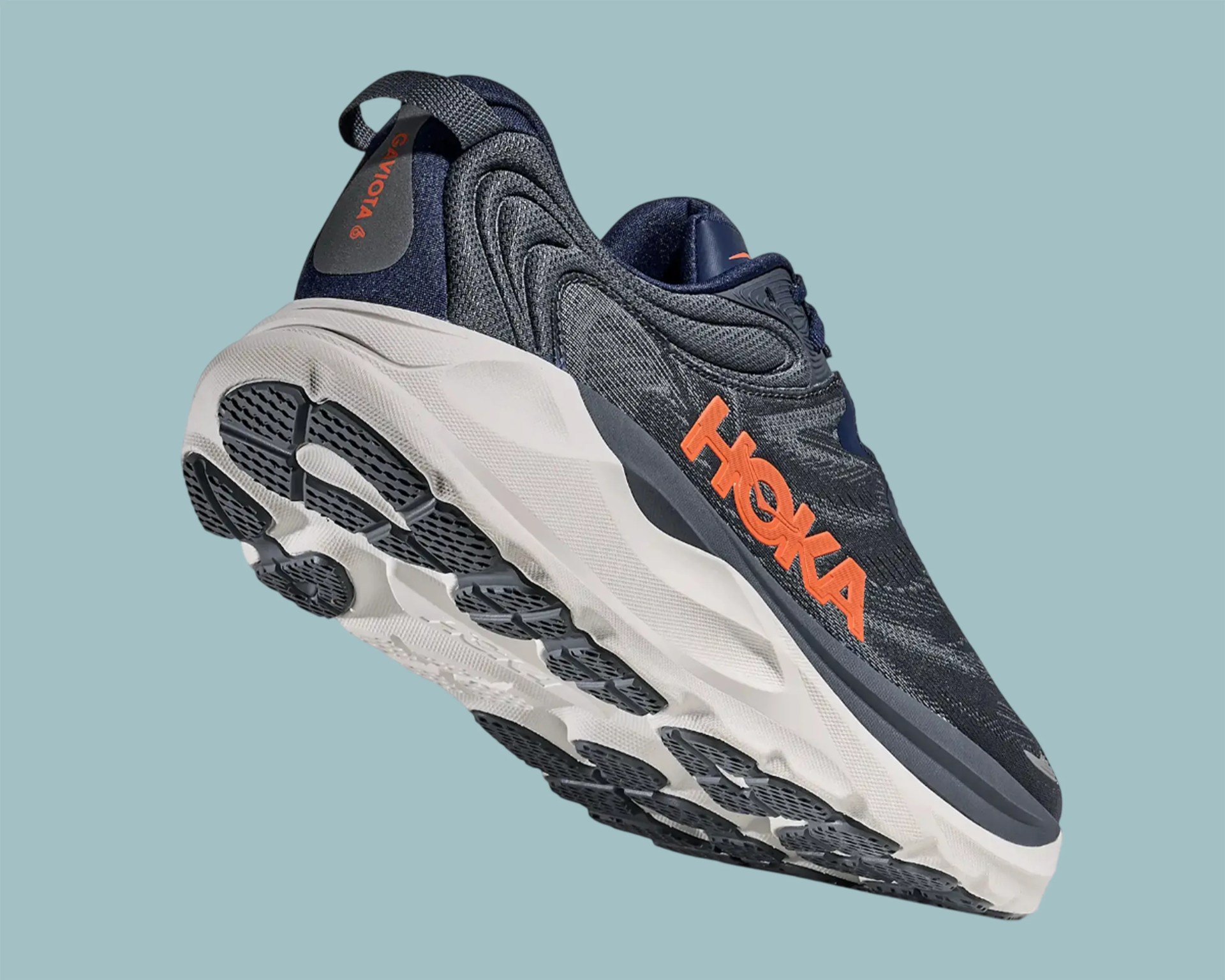 Navy blue and gray Hoka running shoe with orange logo and white textured sole against a light blue background.