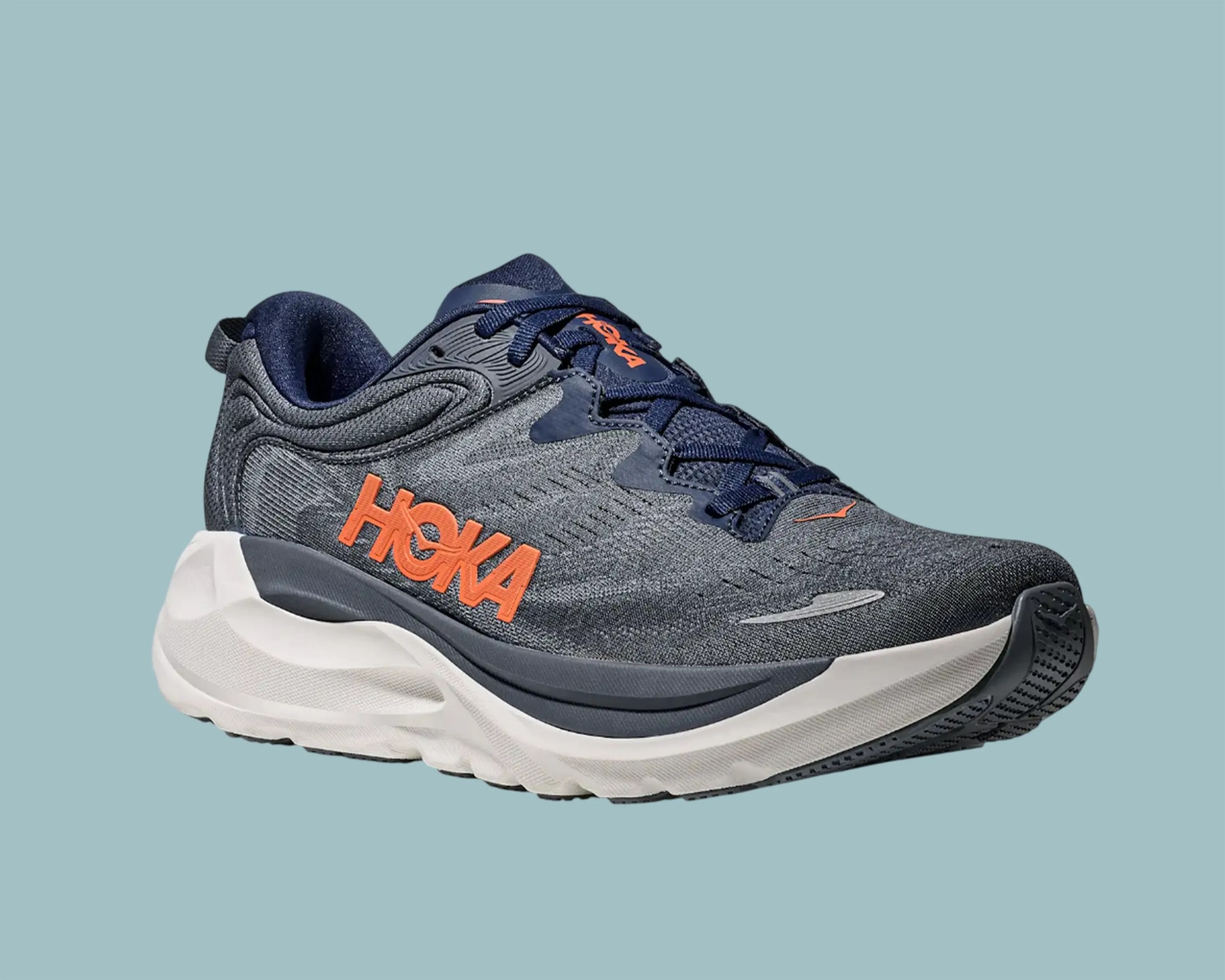 Dark gray and navy Hoka running shoe with orange logo and thick white sole on a light blue background.