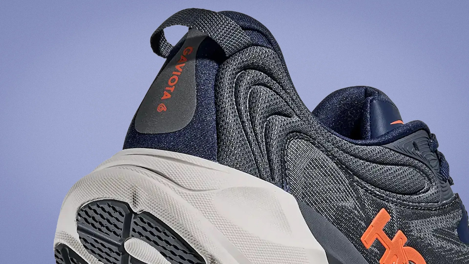 Close-up of the heel and side of a navy and gray sneaker with orange "GAVIOTA 6" text and a white sole.