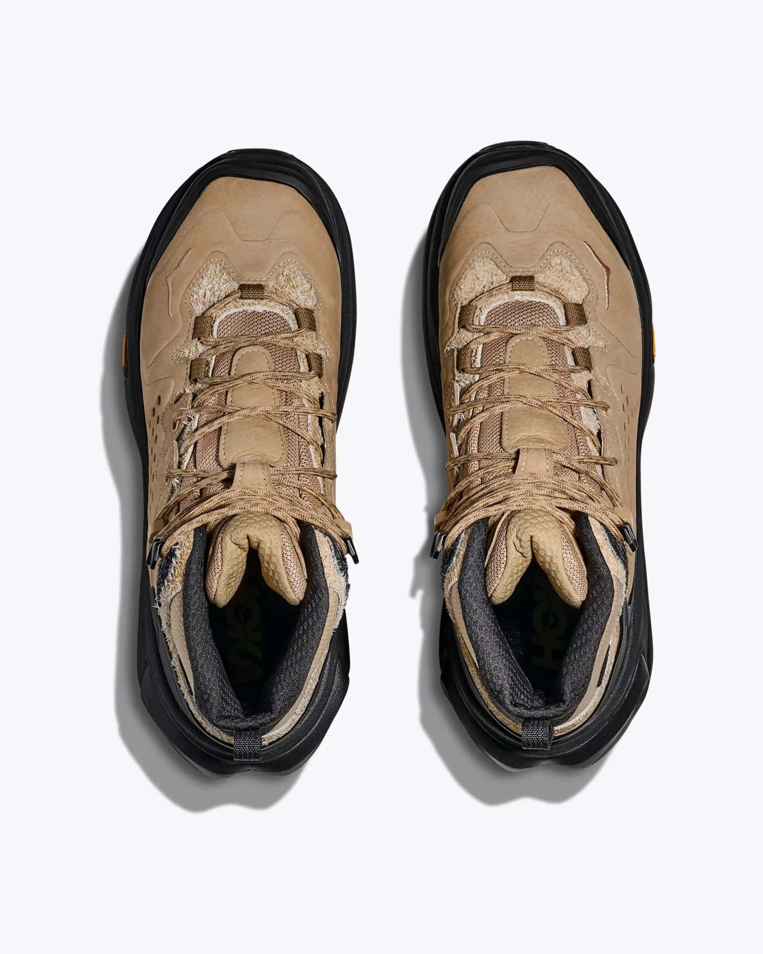 Pair of tan and black hiking boots with mesh and suede uppers viewed from above on a white background.