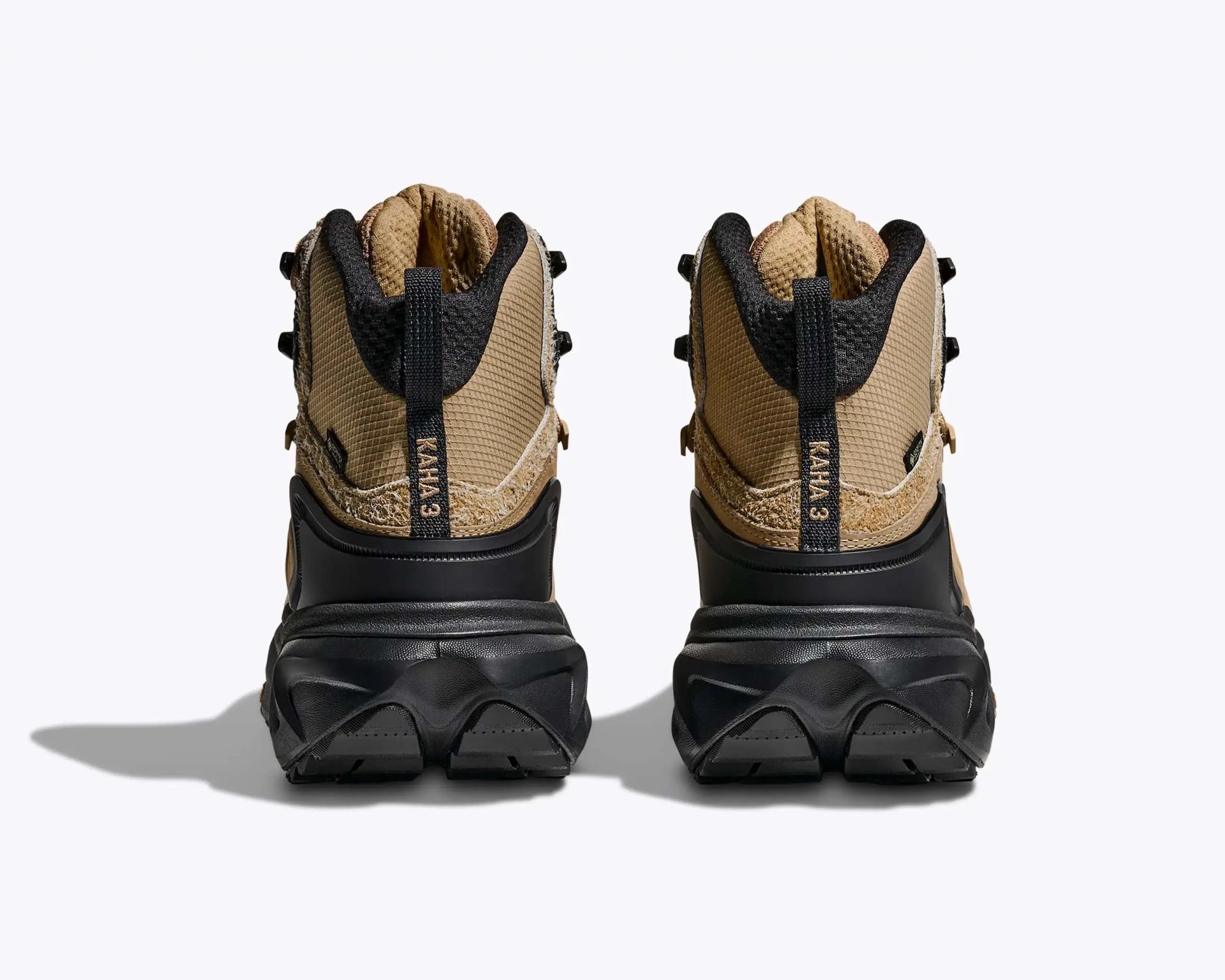 Pair of tan and black hiking boots with black soles viewed from the back on a white background.