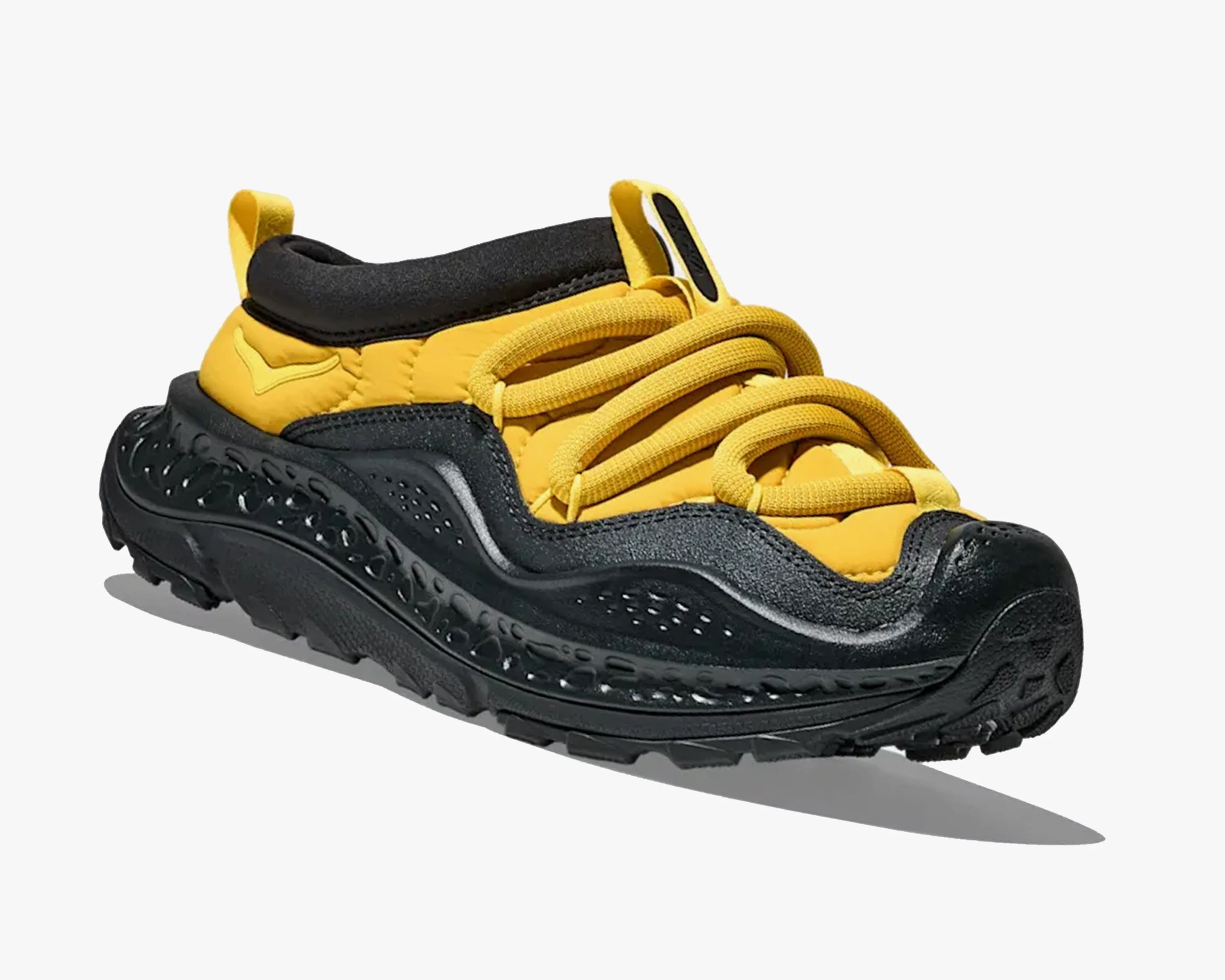 Yellow and black sneaker with thick textured sole and looped laces on a white background.