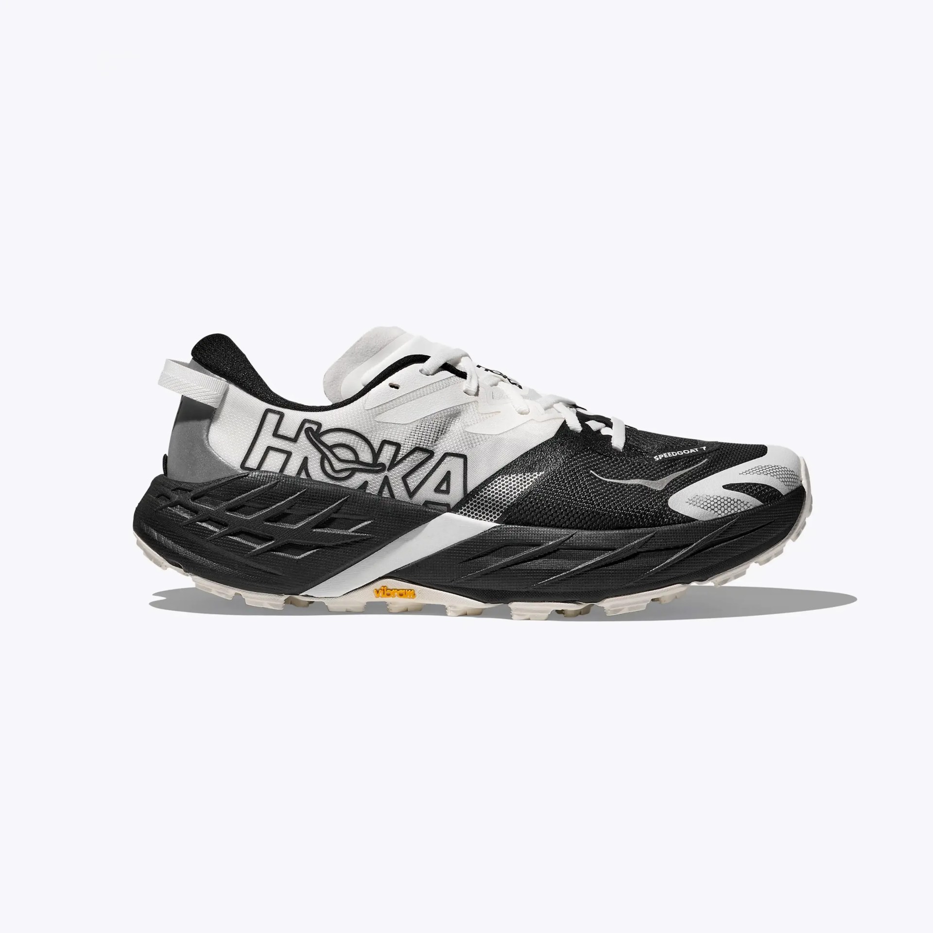 Black and white Hoka Speedgoat 7 trail running shoe with Vibram sole, side view on white background.