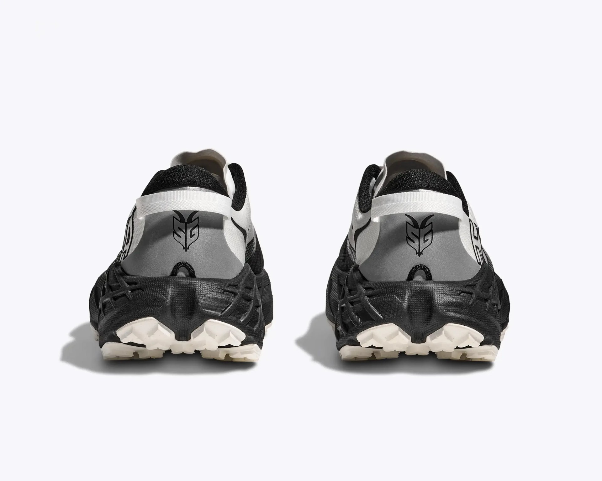 Pair of black and white athletic shoes shown from the back with black soles and a logo on the heel tab.