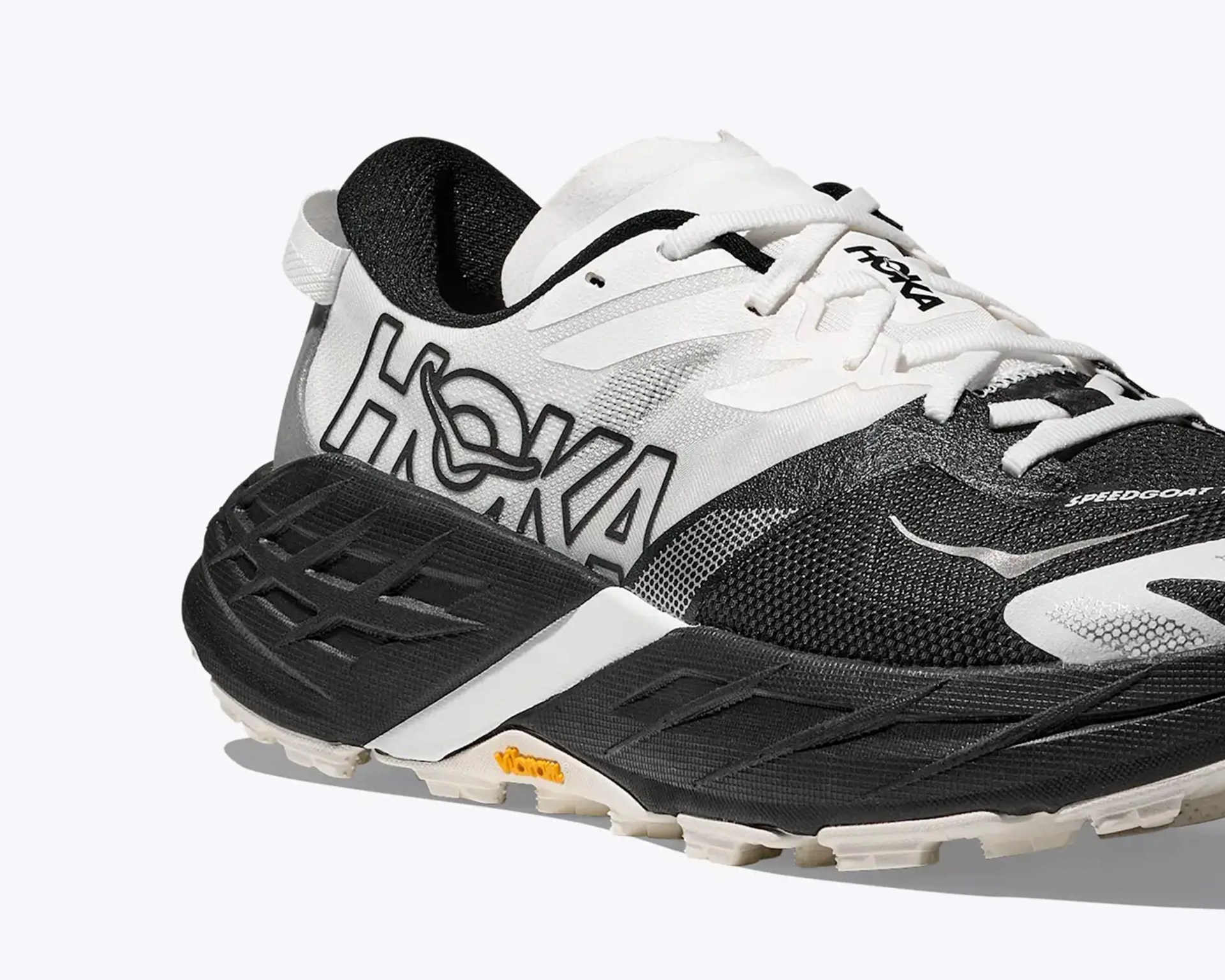 Black and white Hoka Speedgoat trail running shoe with Vibram sole and large logo on the side.