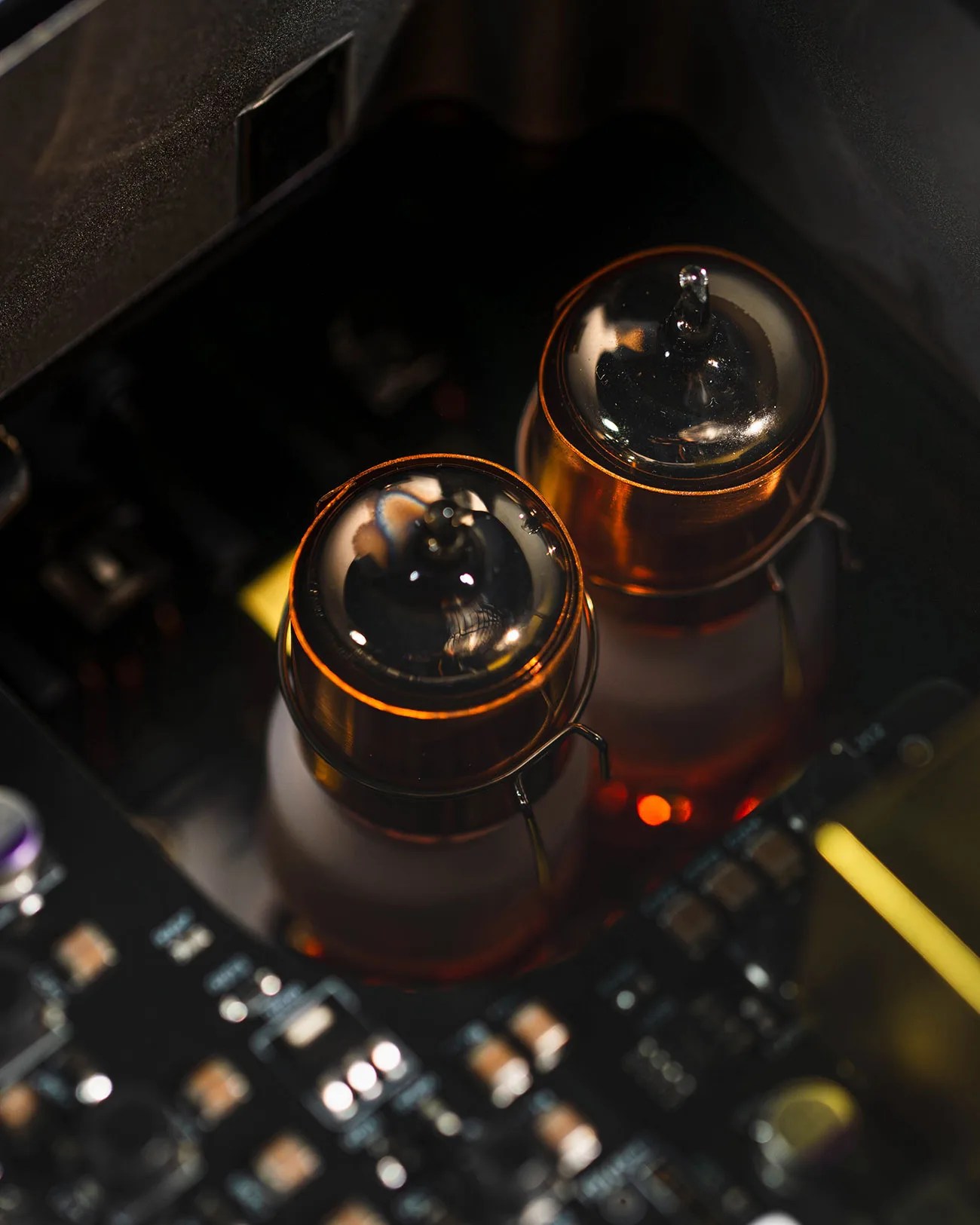 Two glowing vacuum tubes mounted on a black electronic circuit board.