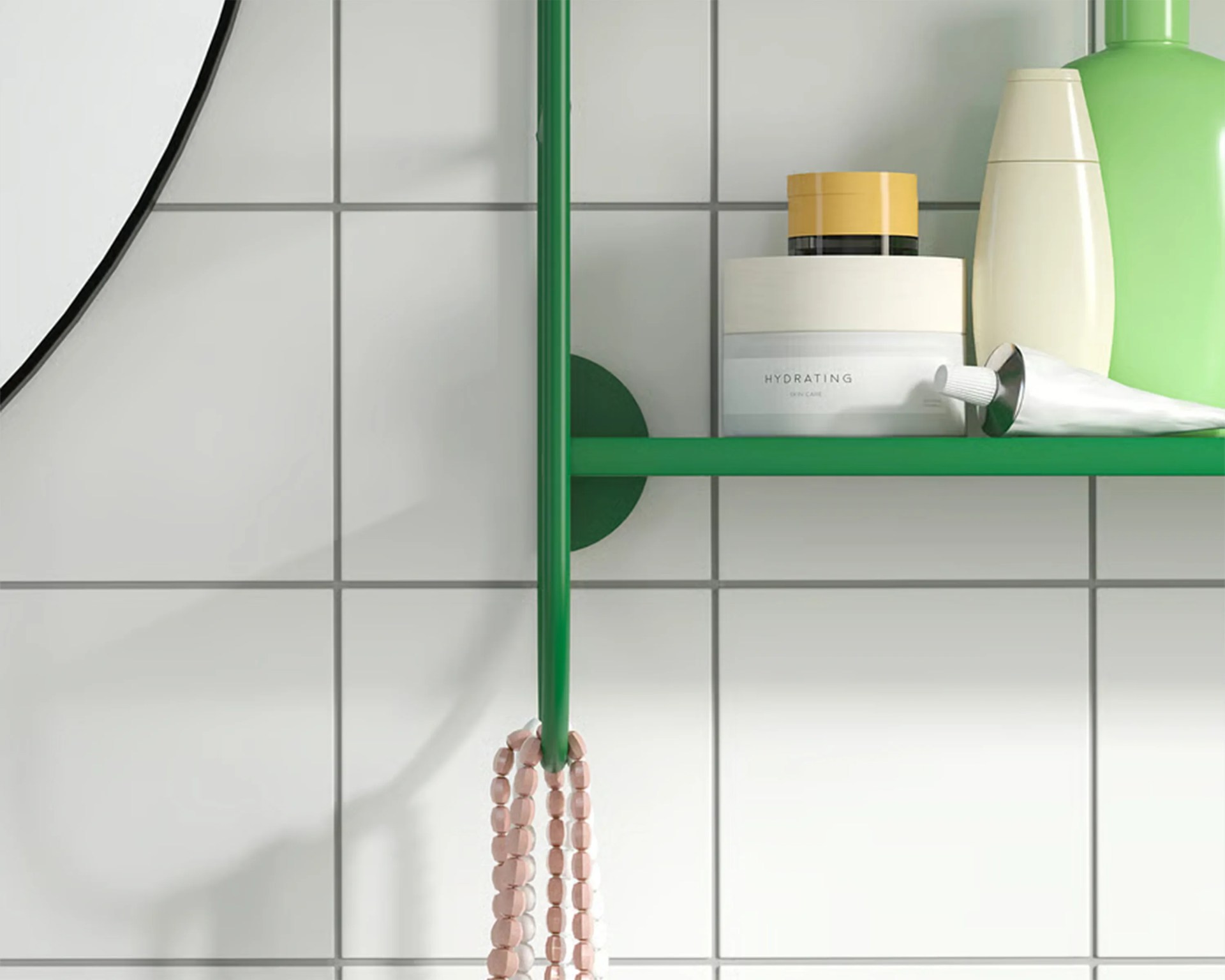 Green metal bathroom shelf with skincare products and a pink beaded necklace hanging on a green hook against white tiled wall.