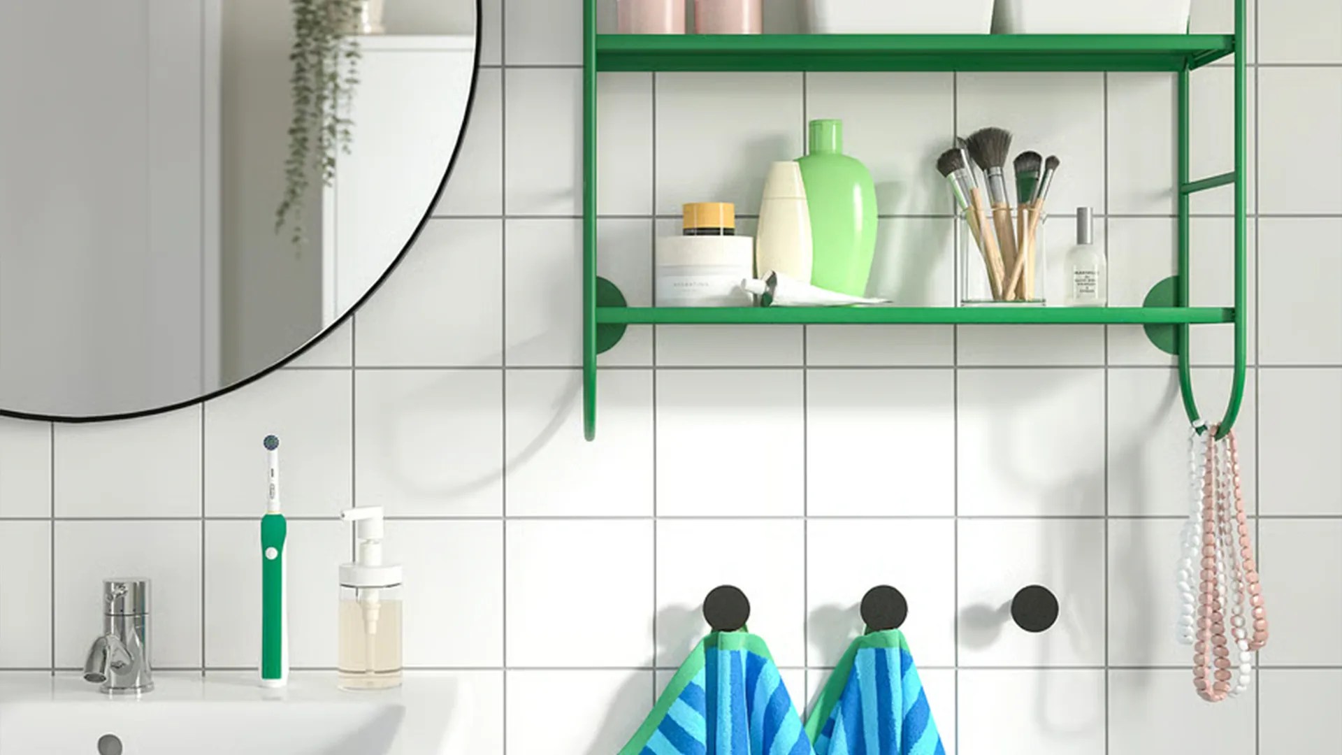 Green wall-mounted shelf with toiletries and makeup brushes above a white tiled bathroom sink with a green and white electric toothbrush.