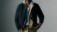 Man wearing layered jackets including a black zip-up jacket, tan jacket, and blue button-up shirt with camouflage pants.