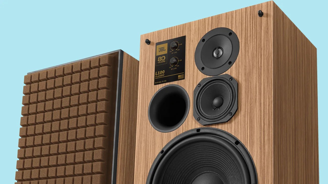 Pair of JBL L100 Classic speakers with wood veneer finish and brown foam grille on one speaker.