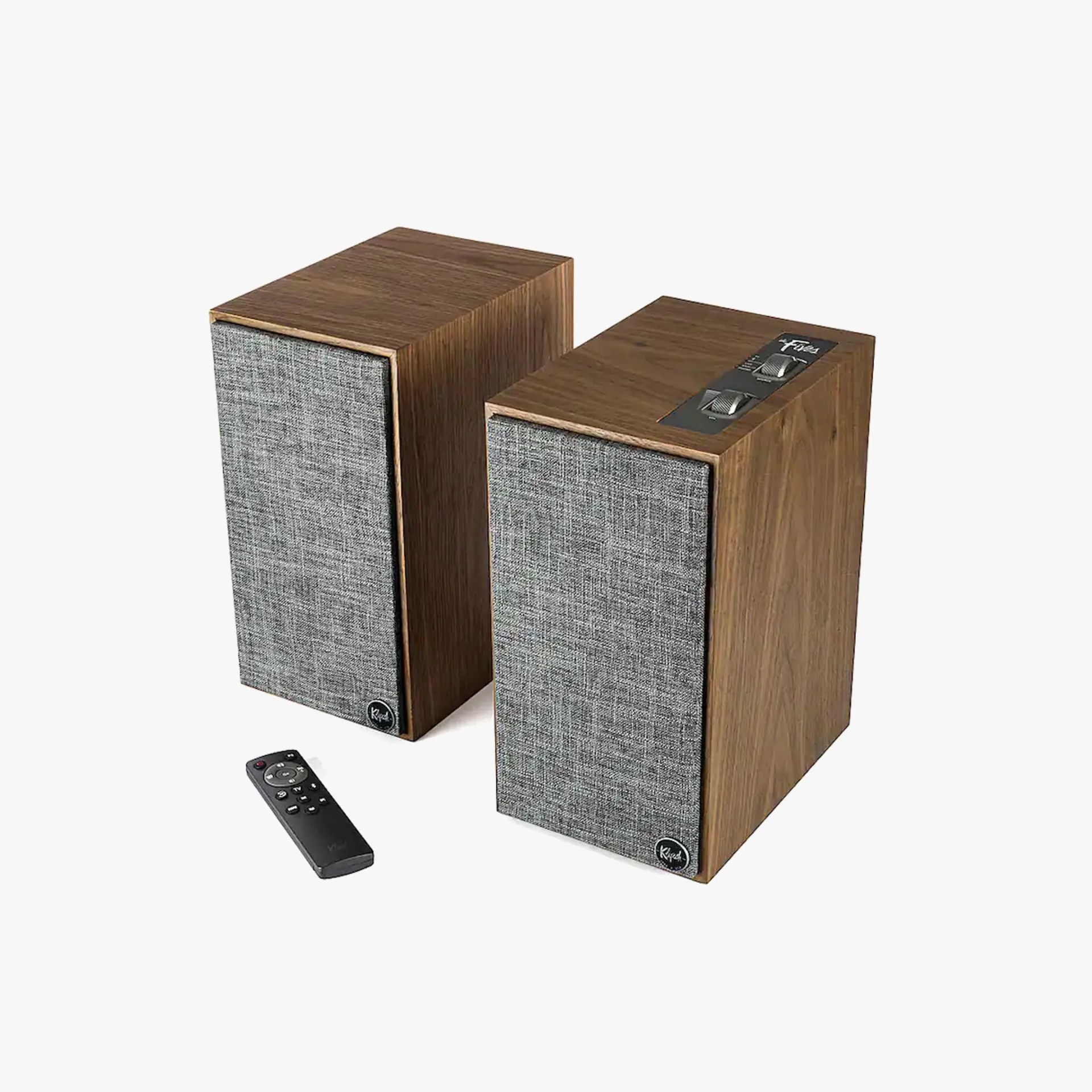 Pair of rectangular wooden speakers with gray fabric fronts and a black remote control on a white background.