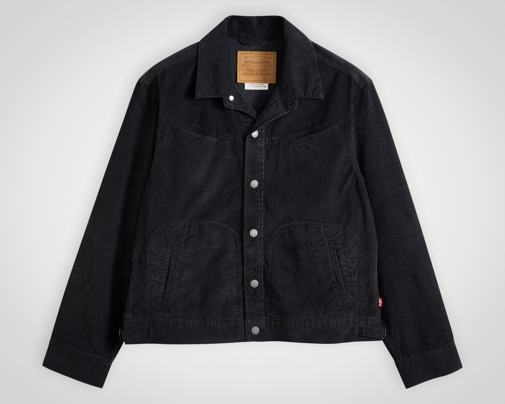Black corduroy Levi's jacket with silver buttons and front pockets laid flat on a white surface.