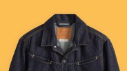 Dark indigo Levi's denim jacket with brown stitching and leather brand patch on a yellow background.