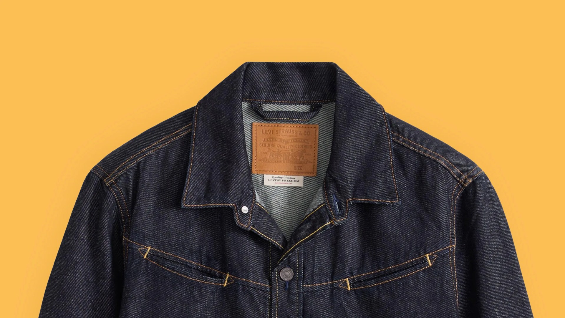Dark indigo Levi's denim jacket with brown stitching and leather brand patch on a yellow background.