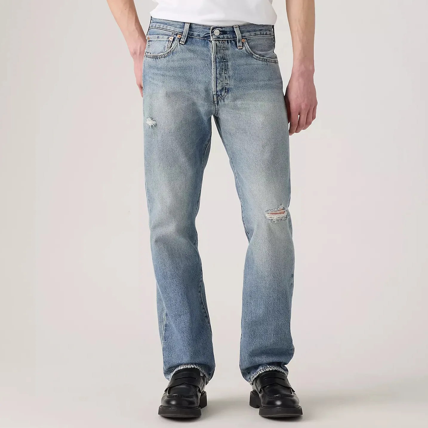 Light blue distressed straight-leg jeans worn with black leather shoes.