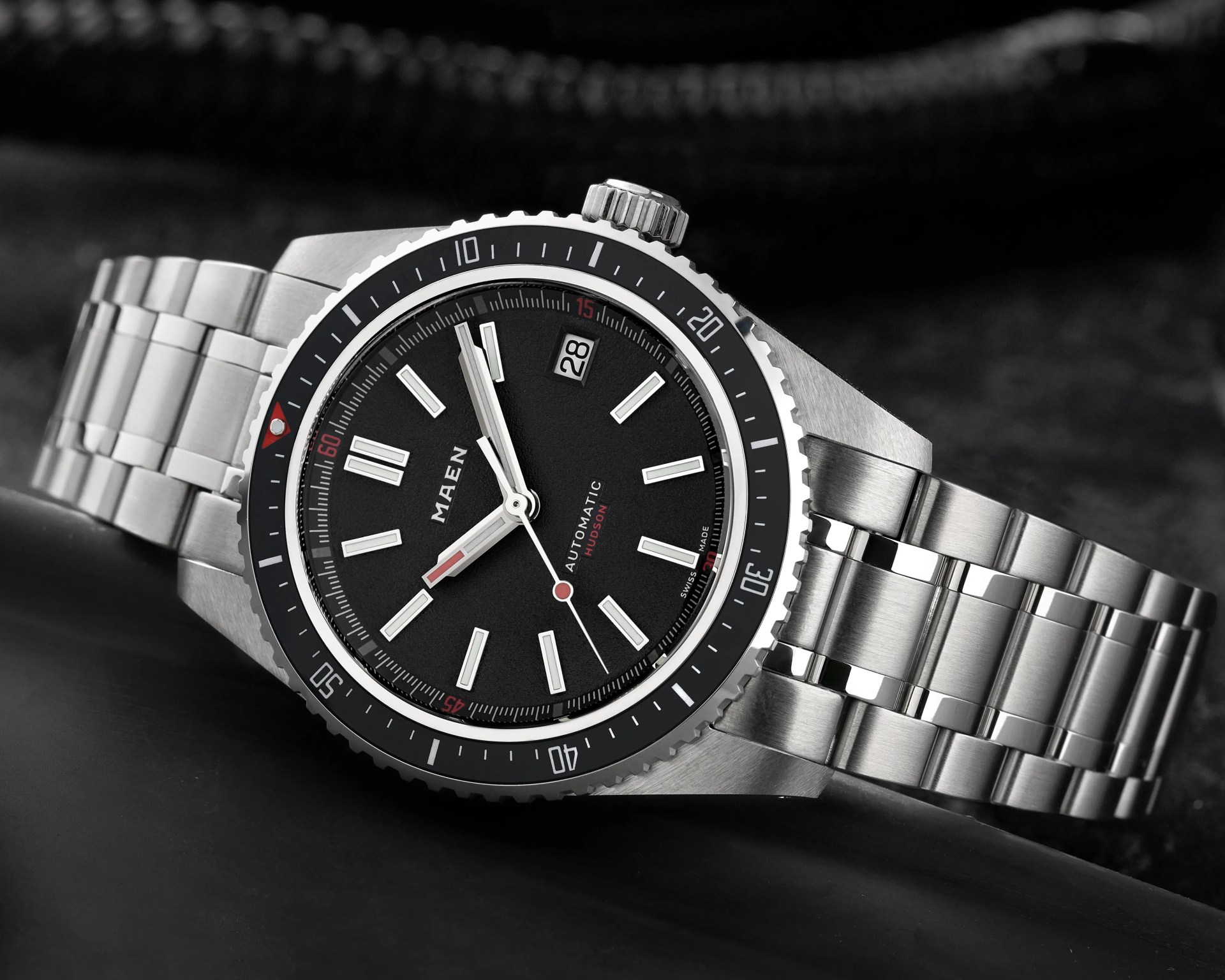 Silver stainless steel wristwatch with black dial, white hour markers, and date display at 2 o'clock.