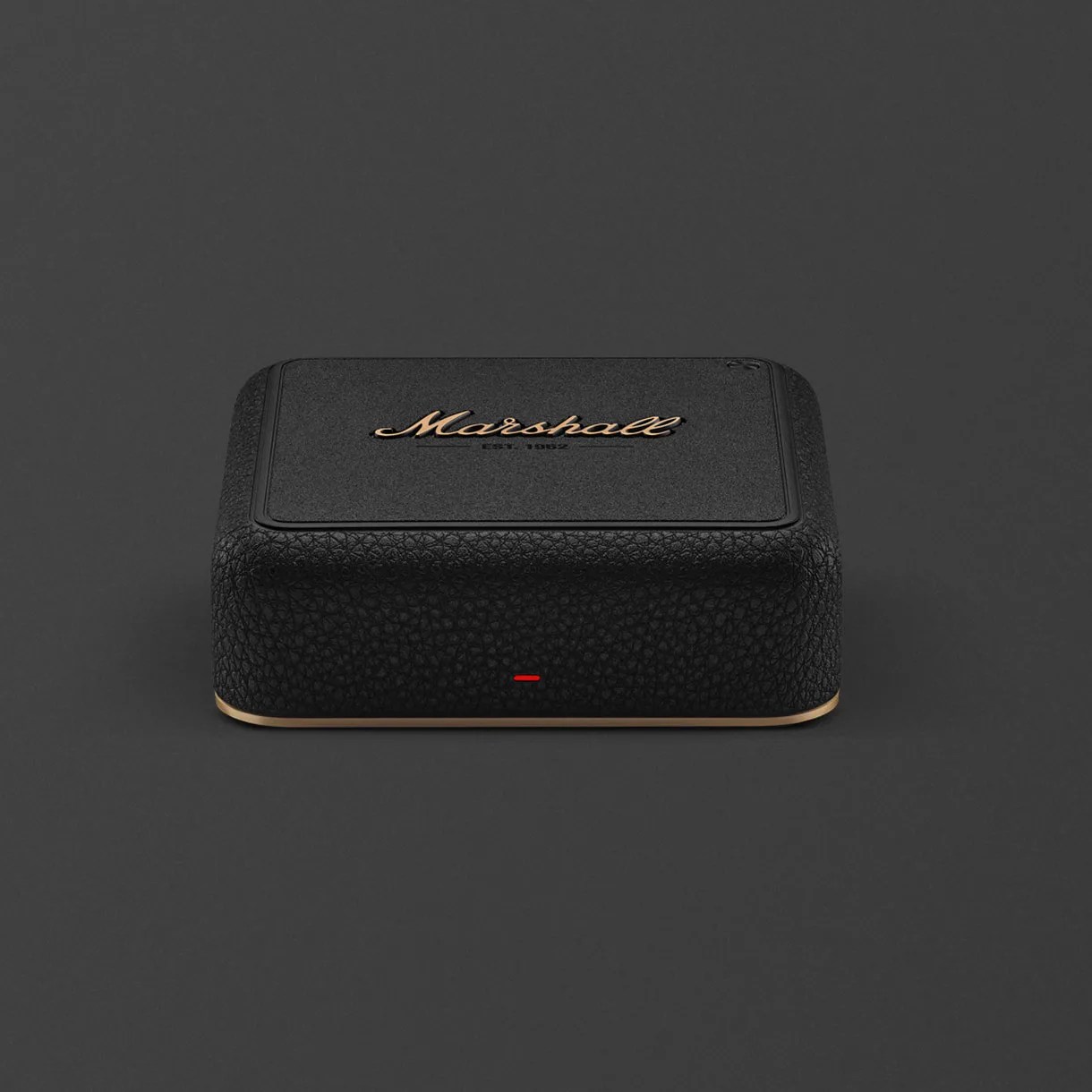 Black textured rectangular Marshall Bluetooth speaker with gold logo and trim on a dark surface.