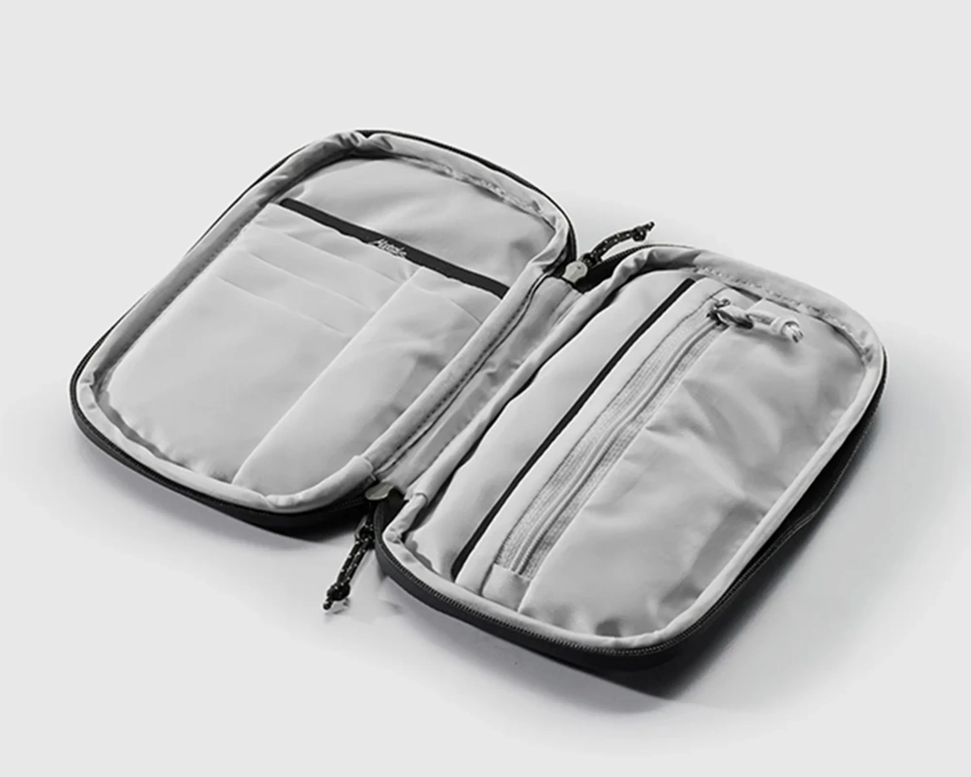Open gray organizer pouch with multiple compartments and a zippered pocket on a white surface.