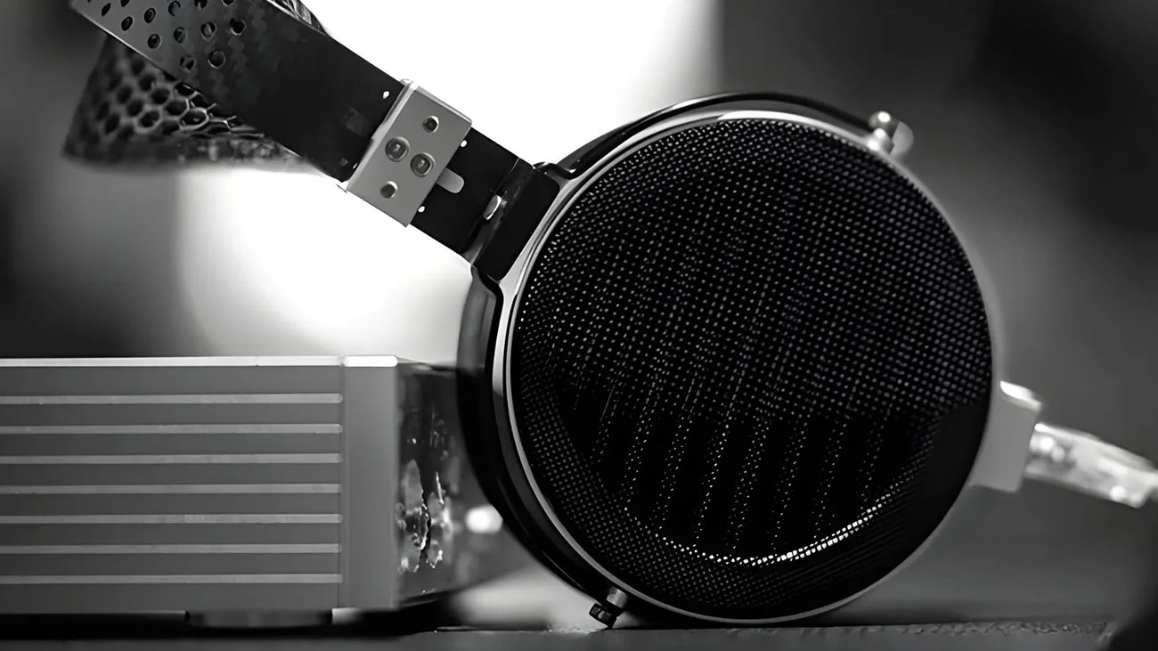 Close-up of black over-ear headphones with a metal mesh grille resting on a silver audio device.