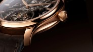 Close-up of a rose gold watch case with visible gears and a brown leather strap.