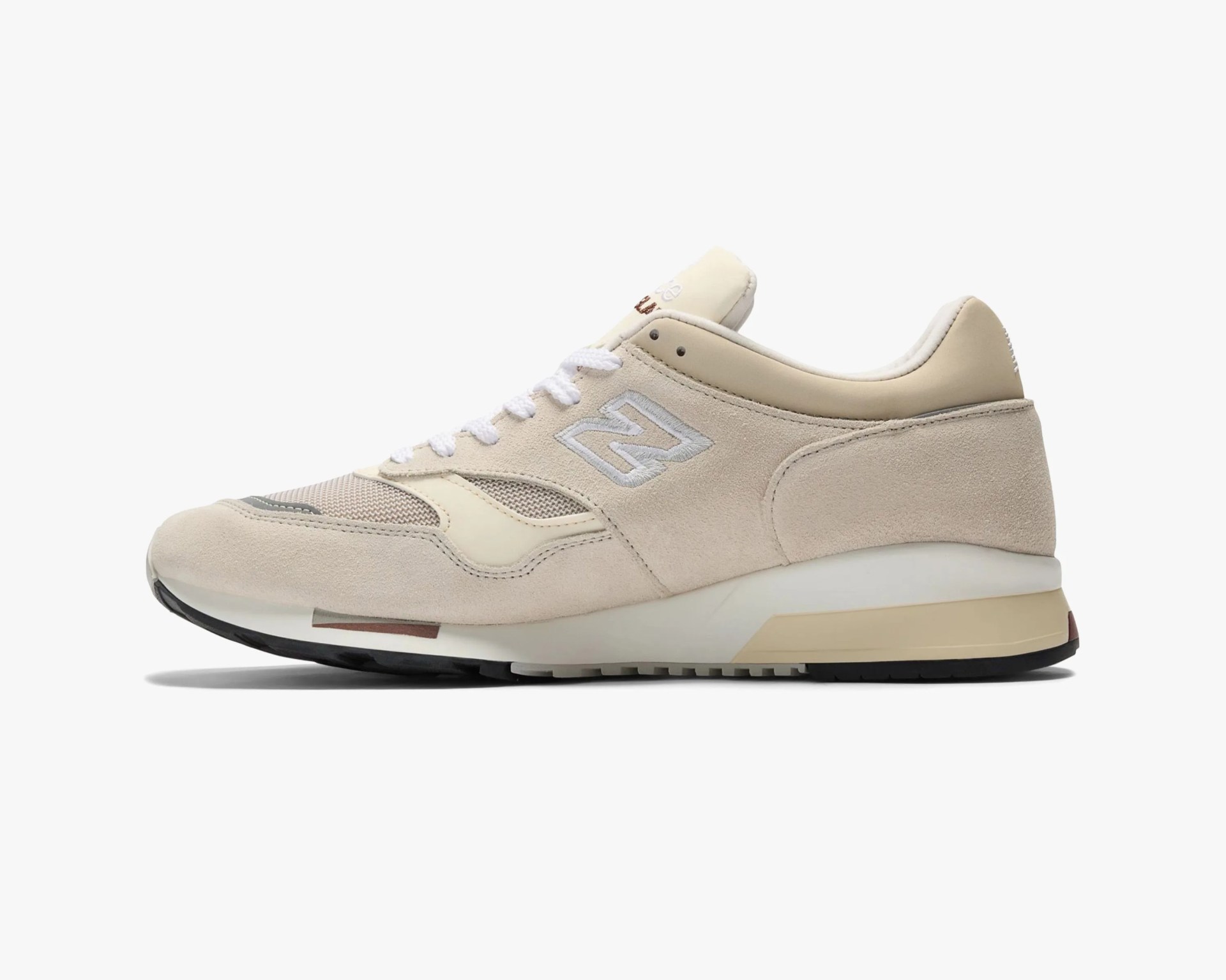 Beige and cream New Balance sneaker with suede and mesh upper and white laces on a white background.