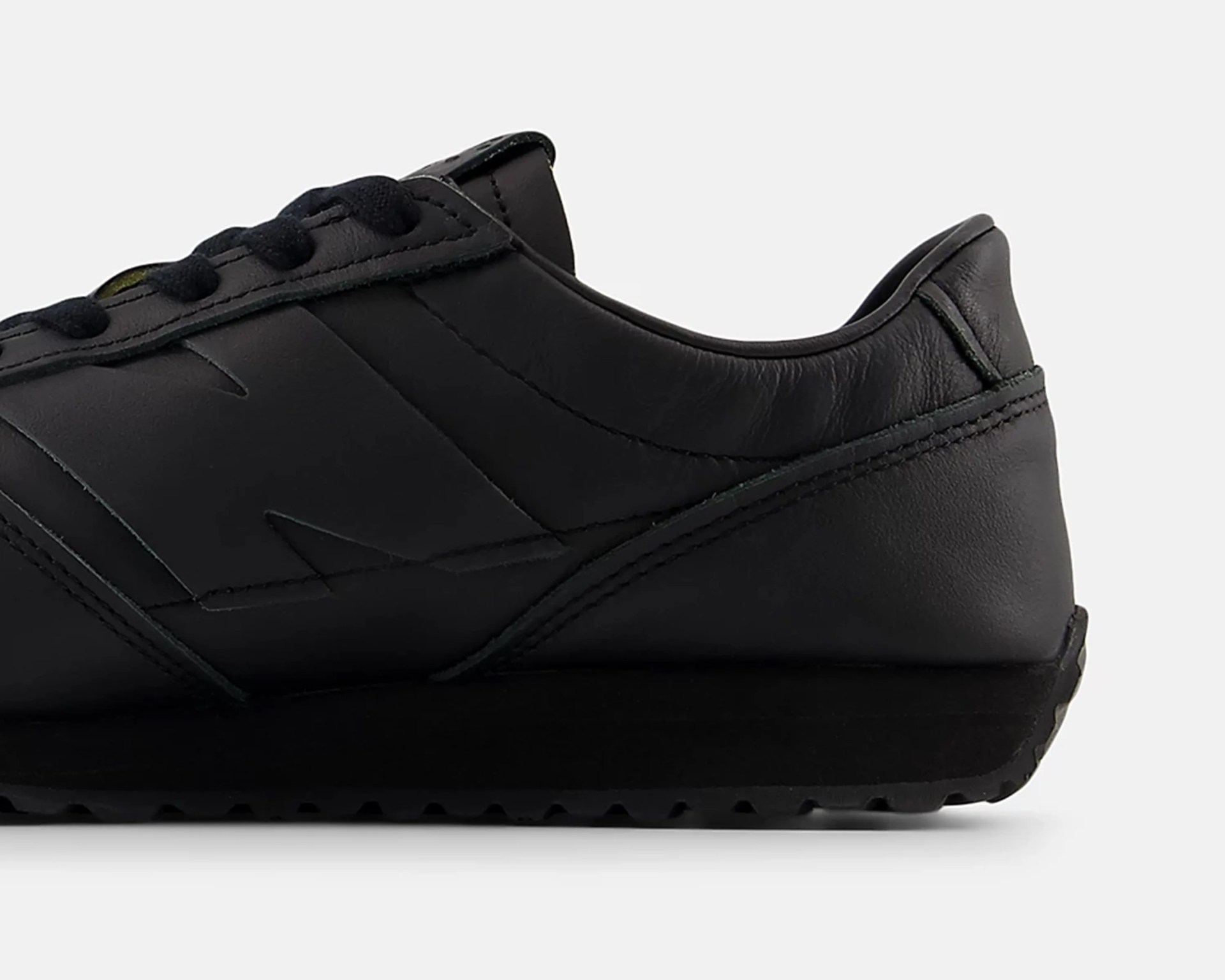 Black leather sneaker with black sole and tonal stitching, side view showing embossed logo.