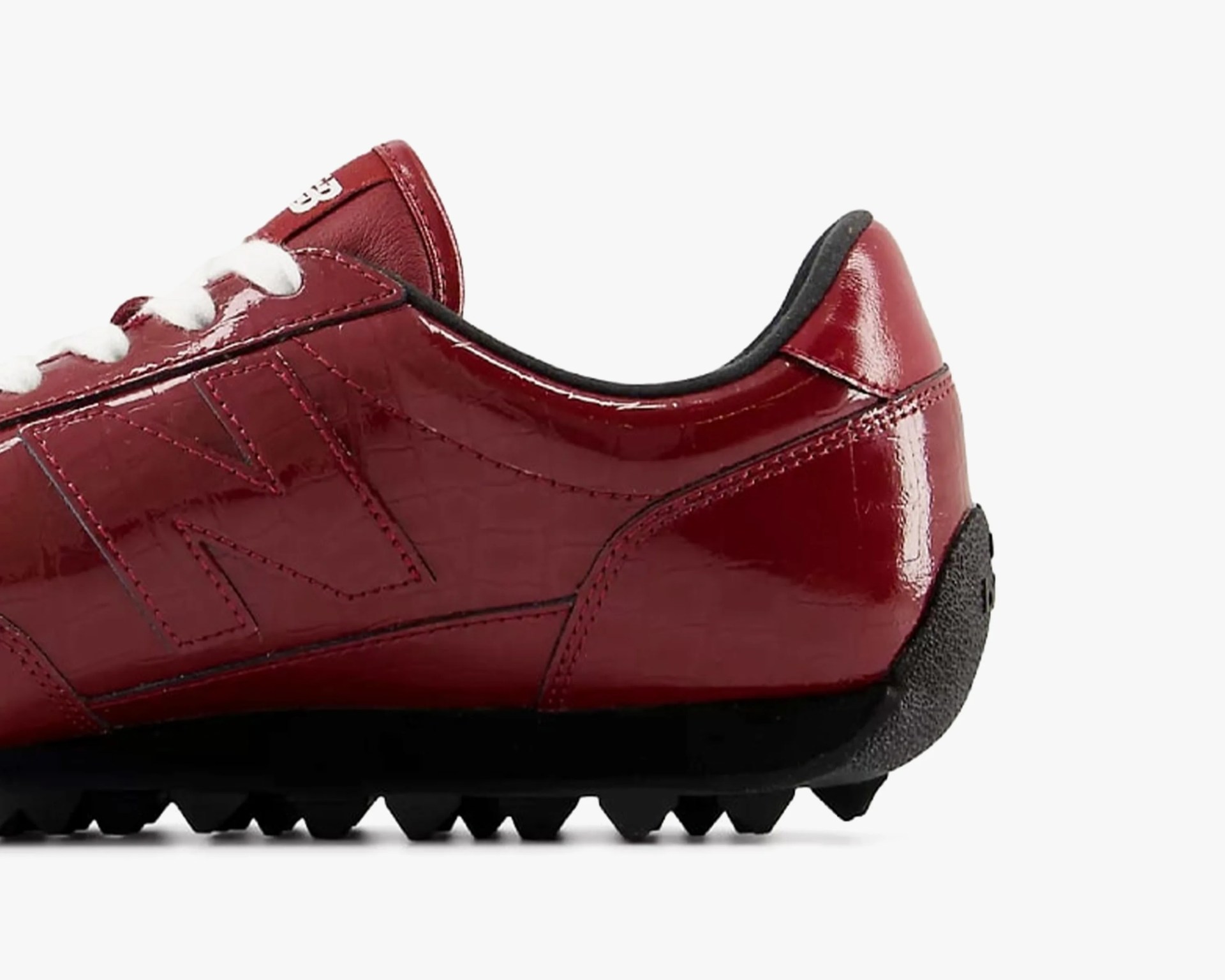 Glossy dark red sneaker with black sole and white laces, showing side and heel details.