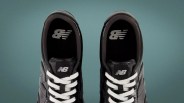 Pair of black New Balance sneakers with white laces viewed from above on a teal background.
