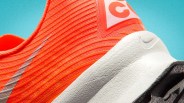 Close-up of an orange Nike running shoe with textured white sole and silver swoosh logo.