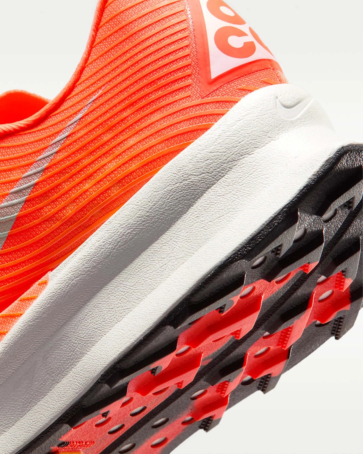 Close-up of an orange Nike running shoe heel with white midsole and black and red textured outsole.