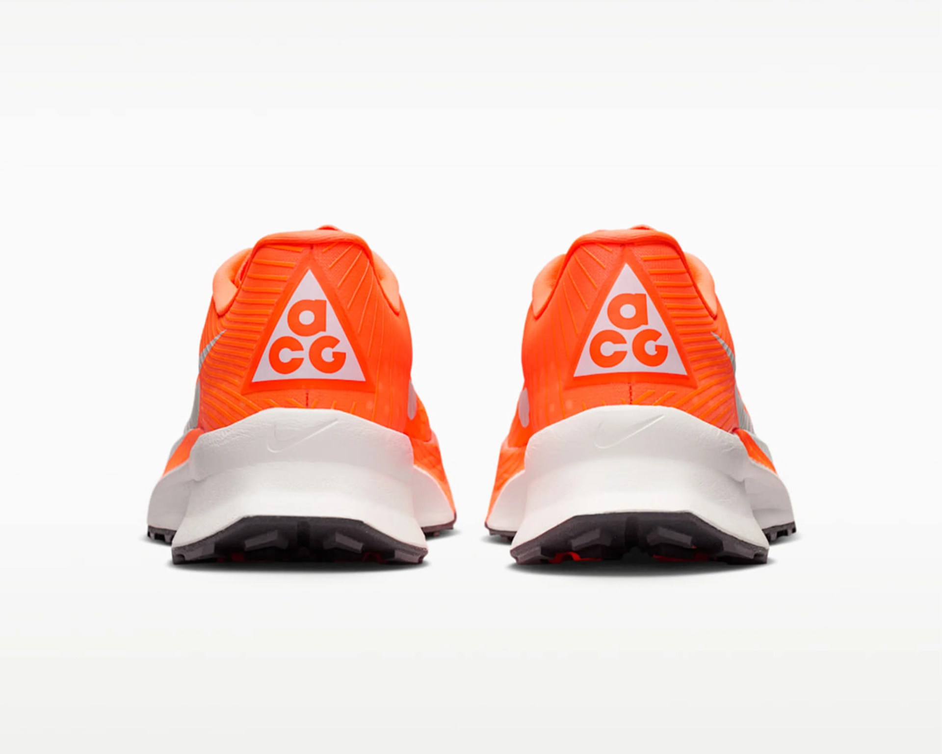 Pair of bright orange Nike ACG sneakers viewed from the back with white midsoles and black outsoles.