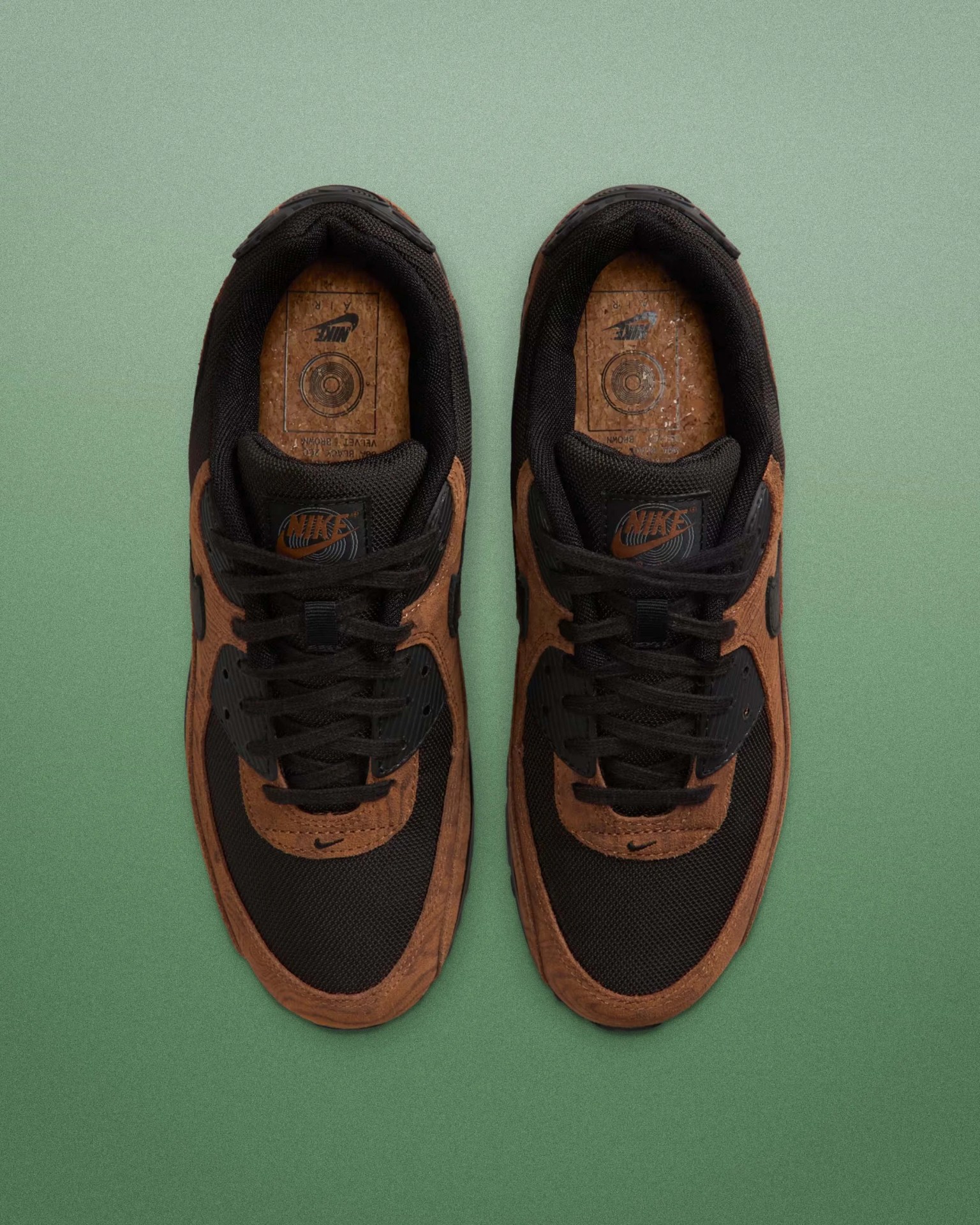 Pair of black and brown Nike sneakers with black laces on a green gradient background.