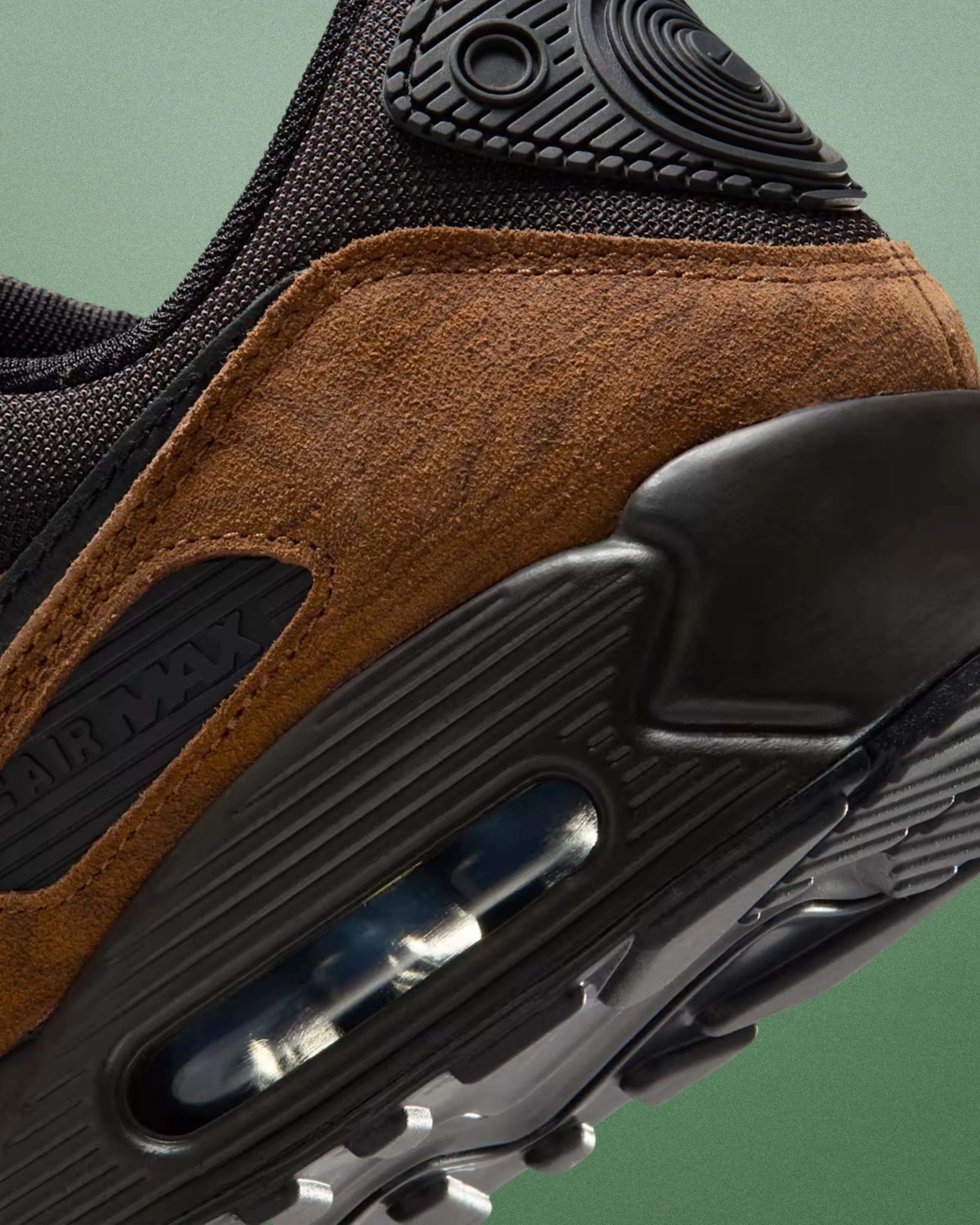 Close-up of a brown suede and black mesh Nike Air Max sneaker heel with visible air cushion in the sole.