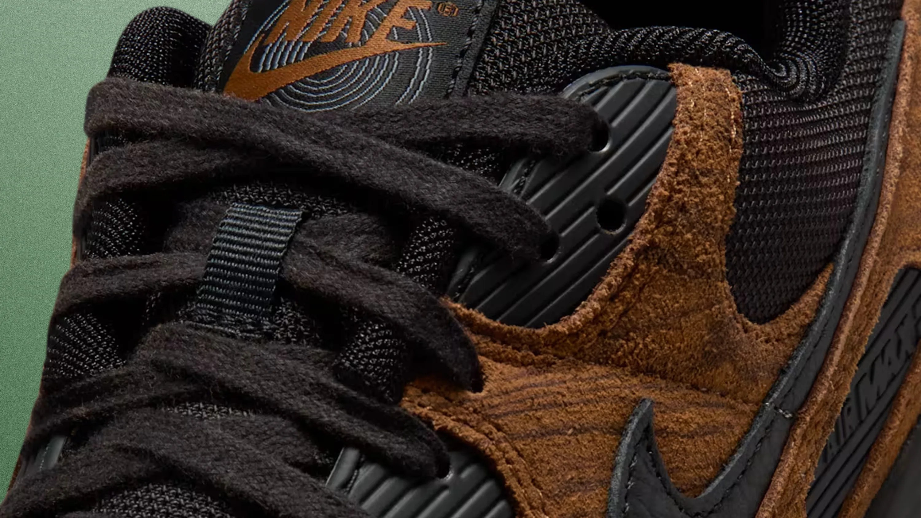 Close-up of black and brown Nike sneaker with suede texture and black laces.