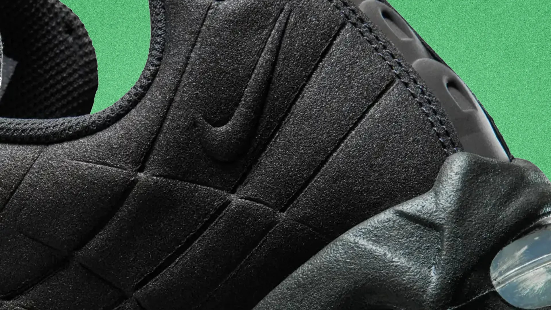 Close-up of black Nike sneaker with textured fabric and visible air cushion in the sole against a green background.